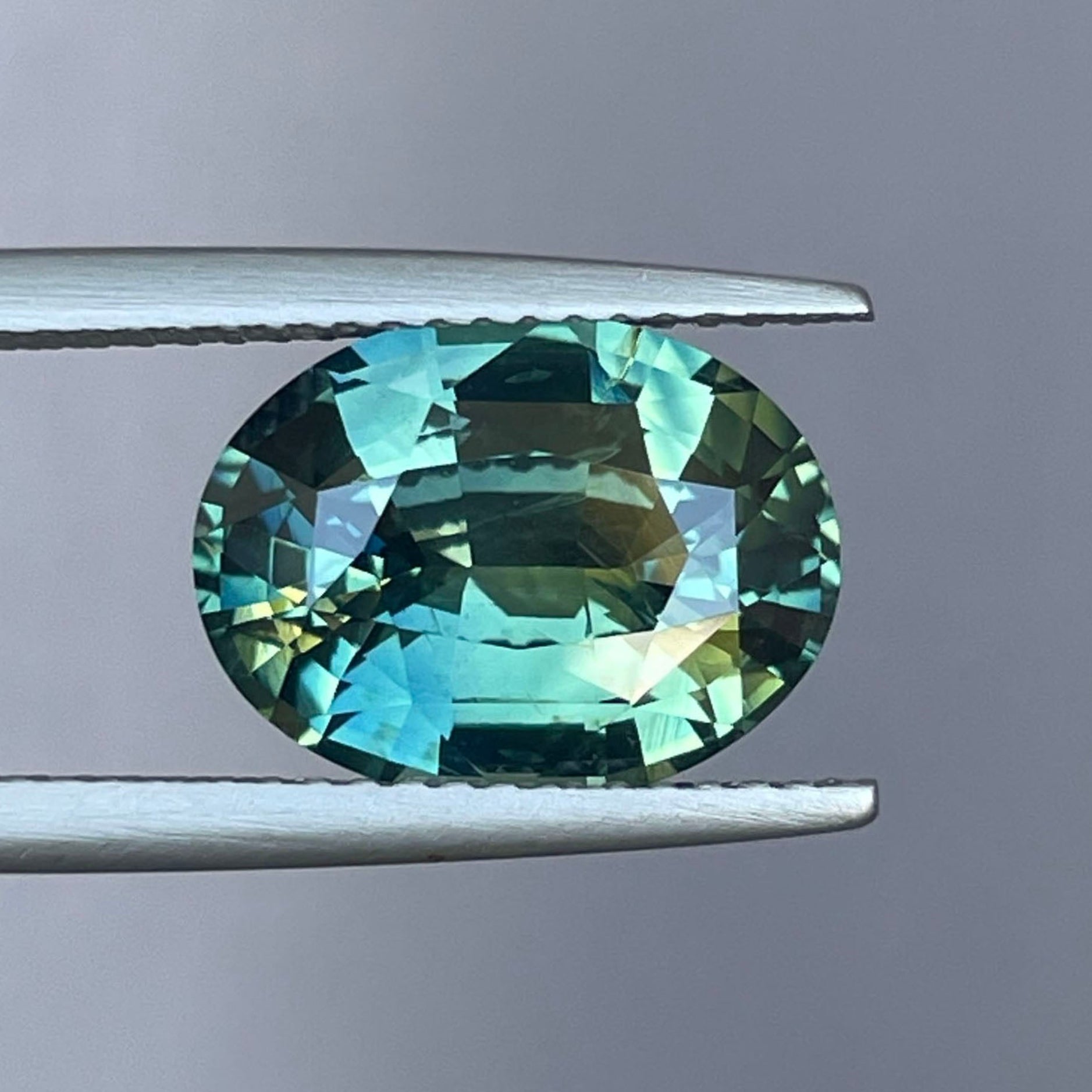 Natural teal blue-green parti sapphire, 5.36 ct oval cut untreated gemstone by NASHGEMS, showcasing vibrant color and clarity.