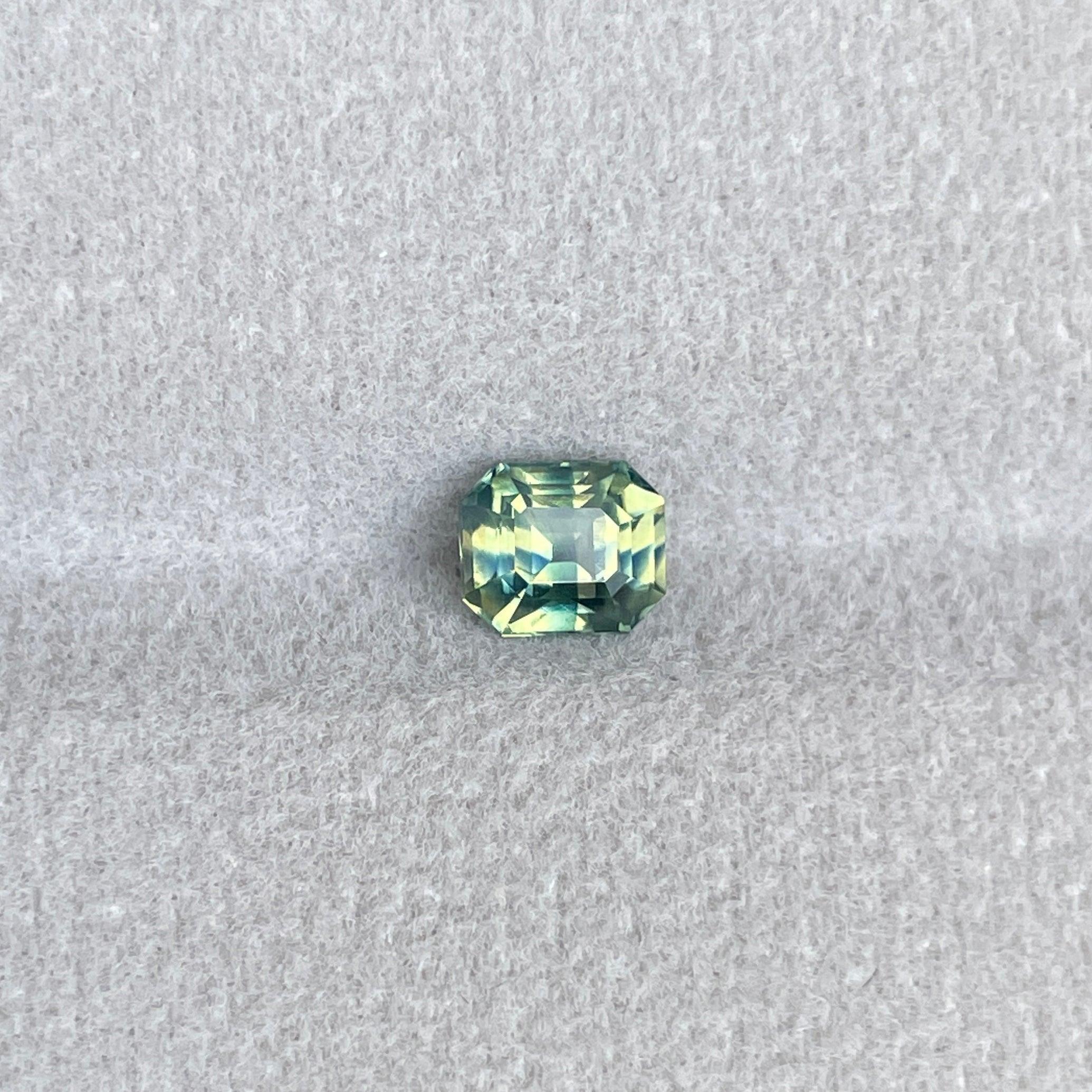 Teal bi-colored parti sapphire gemstone with emerald cut, 1.11 carats, showcasing vibrant green and blue hues, loose precious stone.
