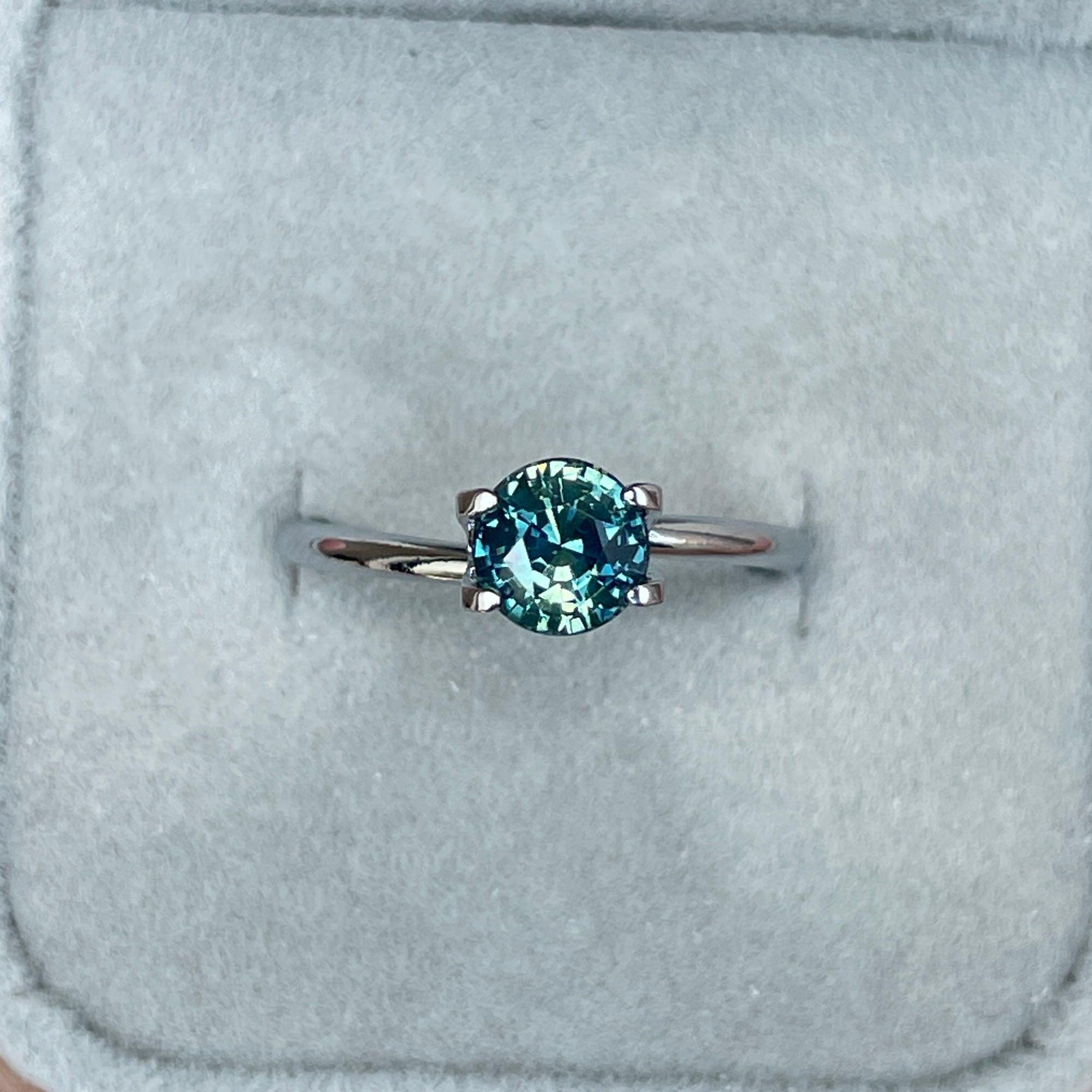 Round teal sapphire from NASHGEMS, 1.31 carats, bi-colored parti sapphire with green and blue hues, perfect September birthstone.
