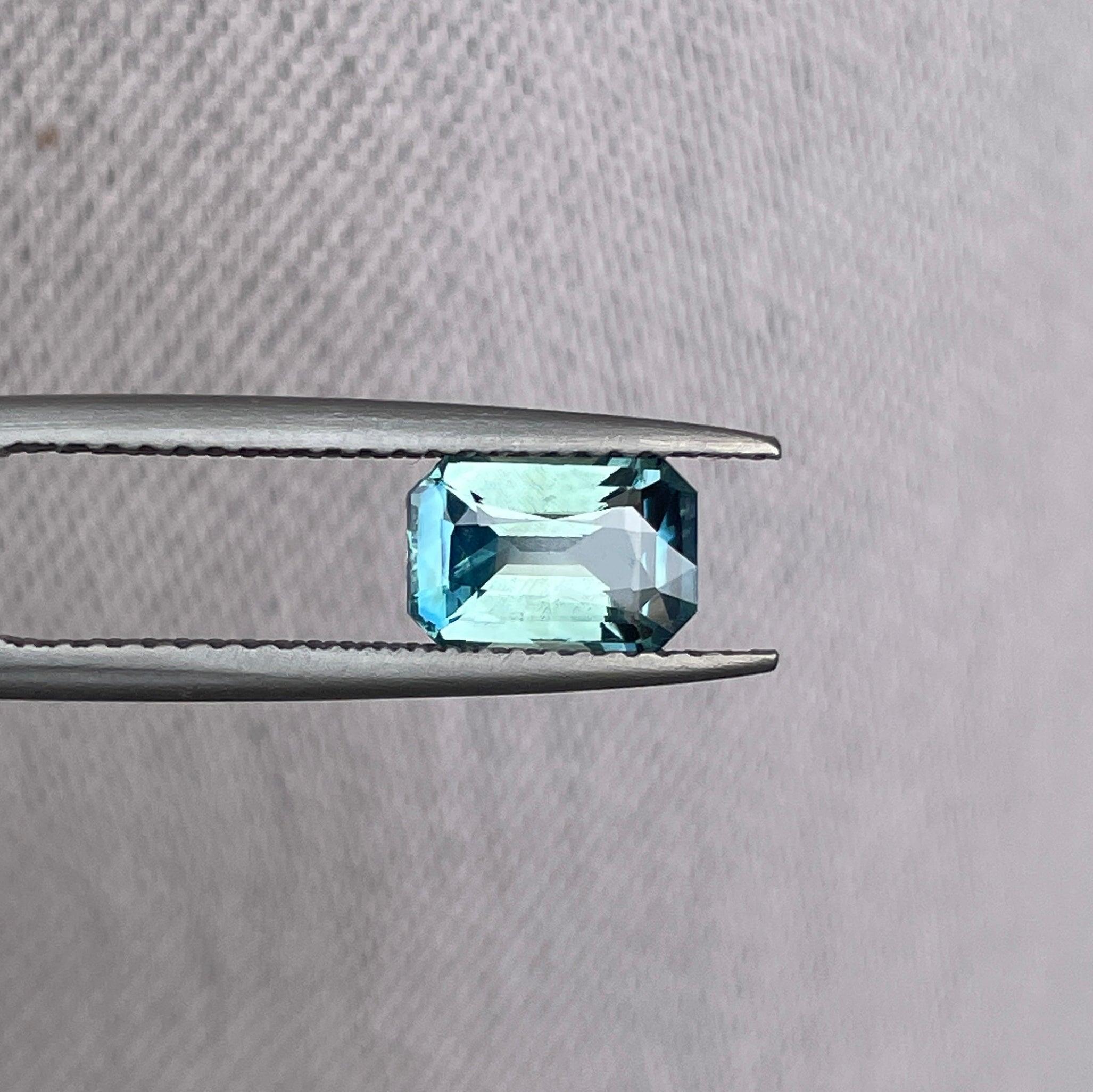 Bi-colored teal sapphire gemstone with emerald cut, 1.54 carats, showcasing vibrant green and blue hues, perfect for September birthstone.