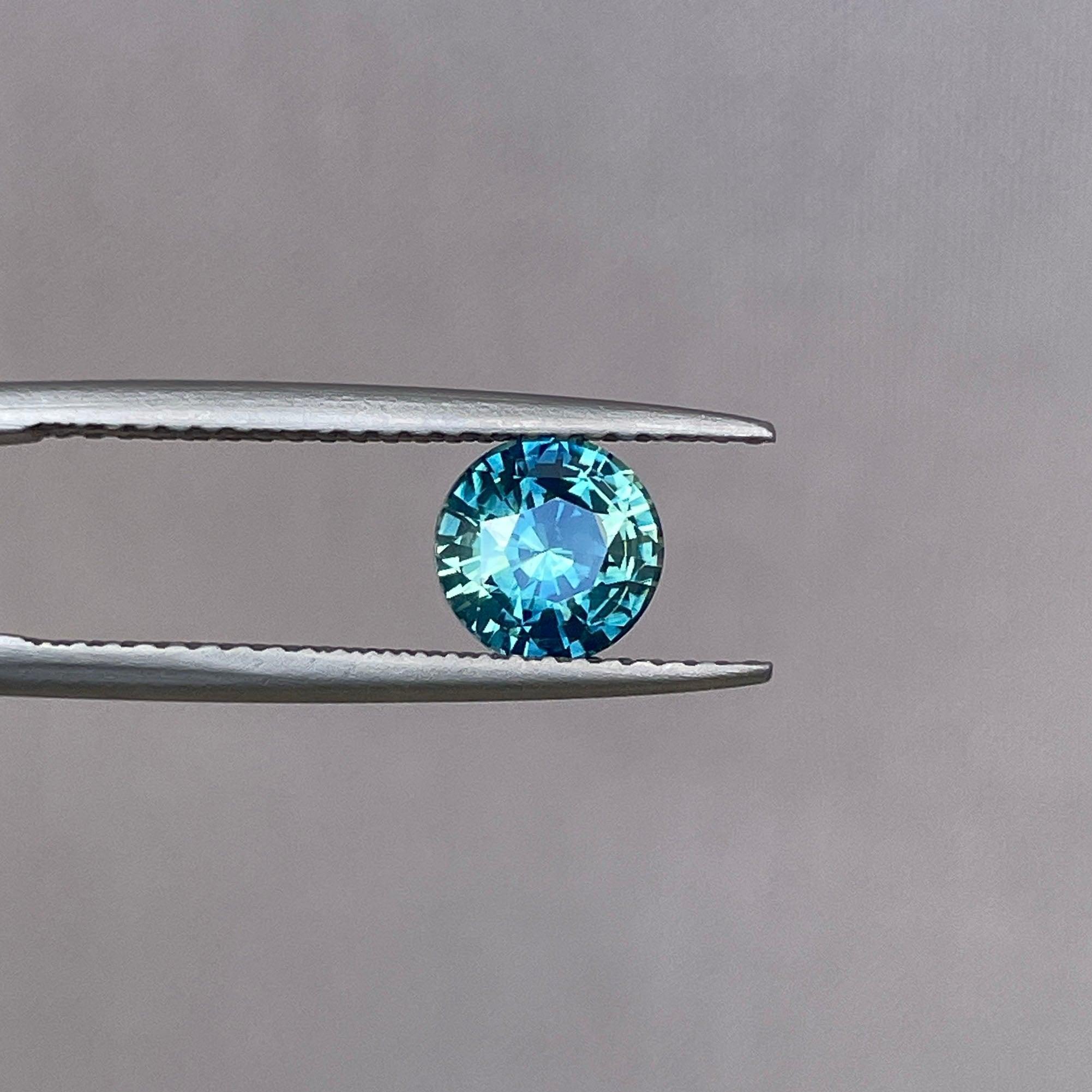 Round 1.31 ct bi-colored teal sapphire with green and blue hues, loose gemstone from NASHGEMS, ideal for September birthstone jewelry.