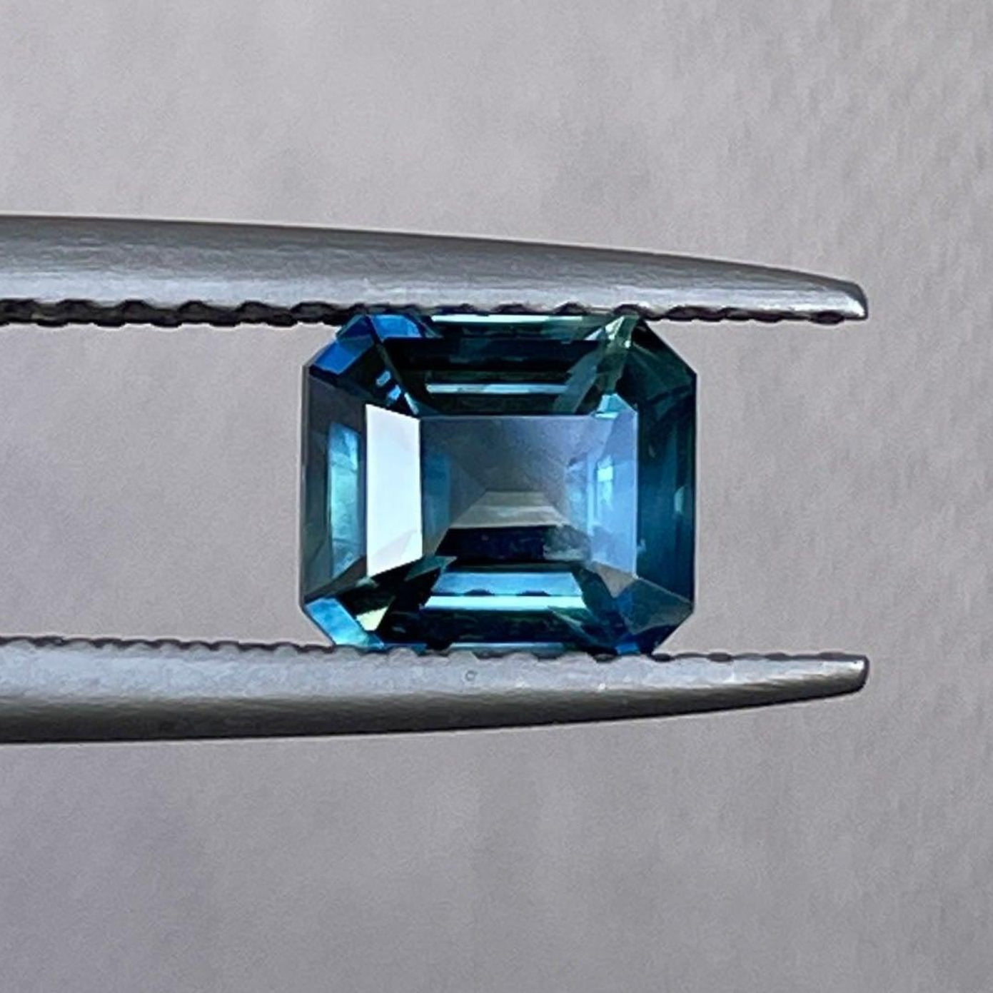 Bague d'anniversaire en saphir bleu-vert sarcelle par NASHGEMS, présentant une taille émeraude et 1,04 carat, parfaite pour les fiançailles ou les occasions spéciales.