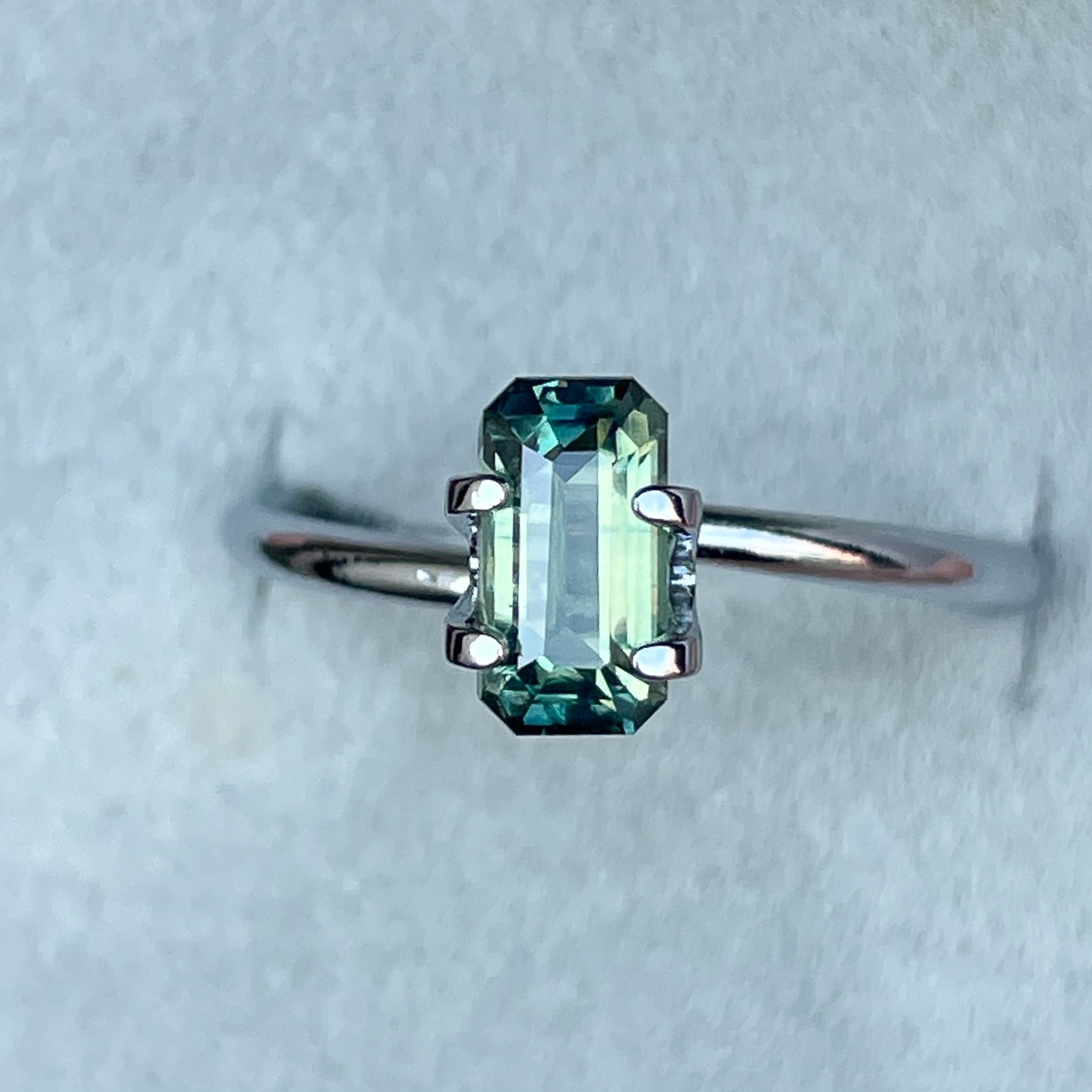 Teal sapphire loose stone with emerald cut, 1.49 carats, from NASHGEMS, featuring vibrant green and blue hues, perfect as September birthstone.