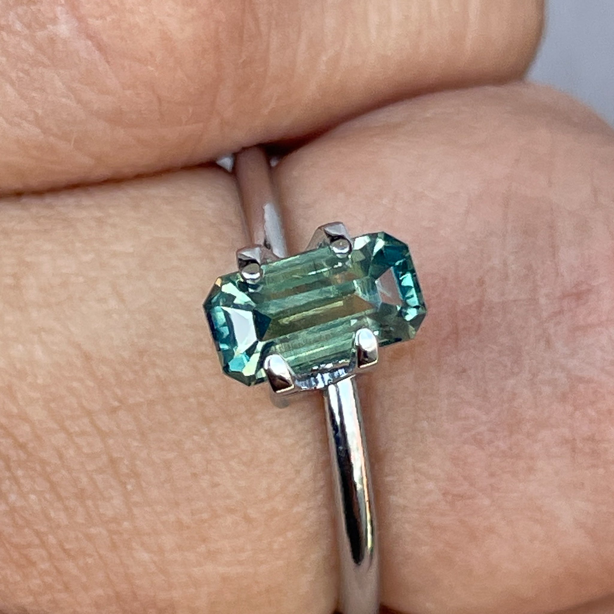 Teal sapphire loose stone with emerald cut, 1.49 carats, from NASHGEMS, showcasing vibrant green and blue parti sapphire for September.