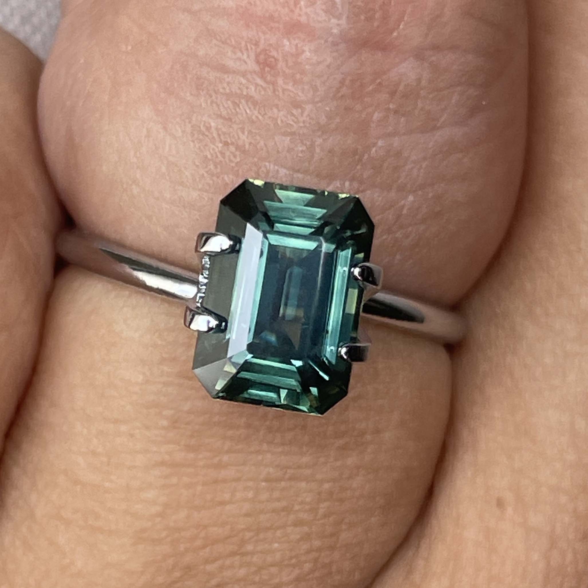 Natural green sapphire 3.03 Ct emerald cut loose gemstone from NASHGEMS, showcasing vibrant teal color and clear gemstone details.