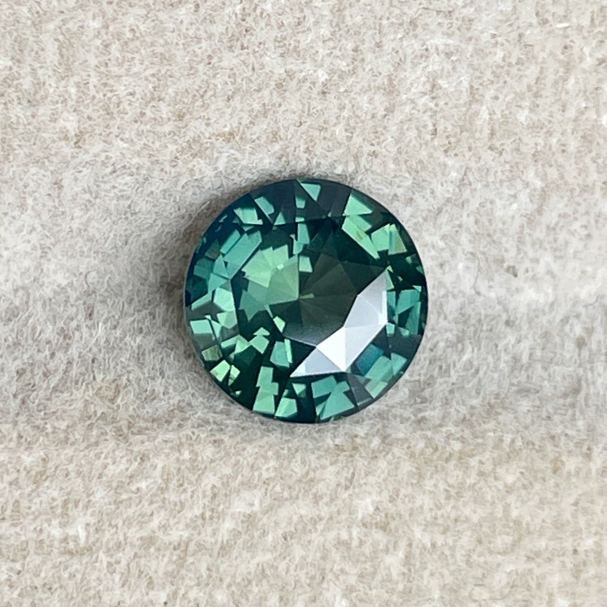 Teal natural forest green sapphire, 1.83 carats, round cut, loose gemstone from NASHGEMS for engagement or custom jewelry.