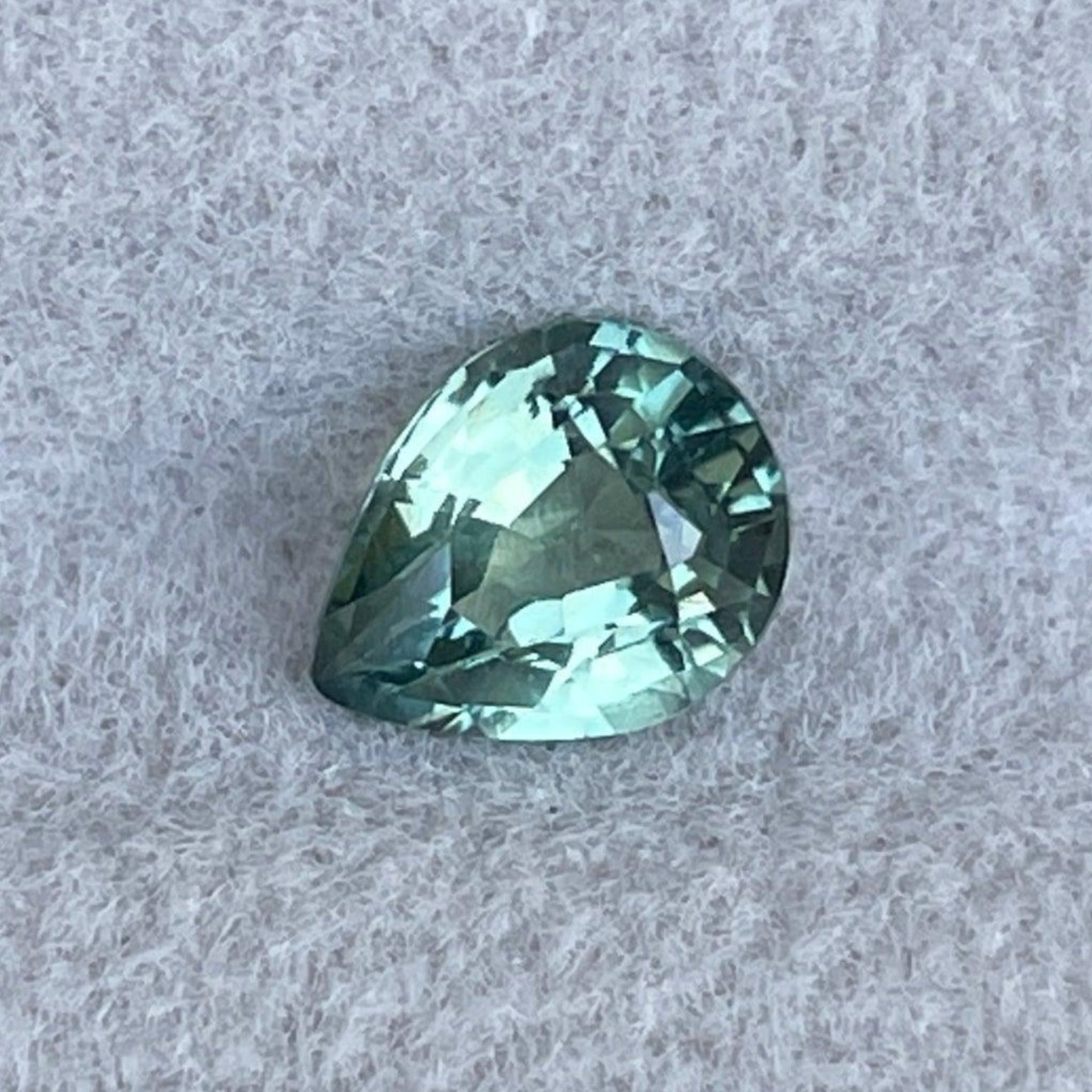 Pierre précieuse saphir vert naturel de NASHGEMS, saphir poire de 0,89 ct couleur sarcelle avec des nuances vert menthe foncé et clair ainsi que vert olive.