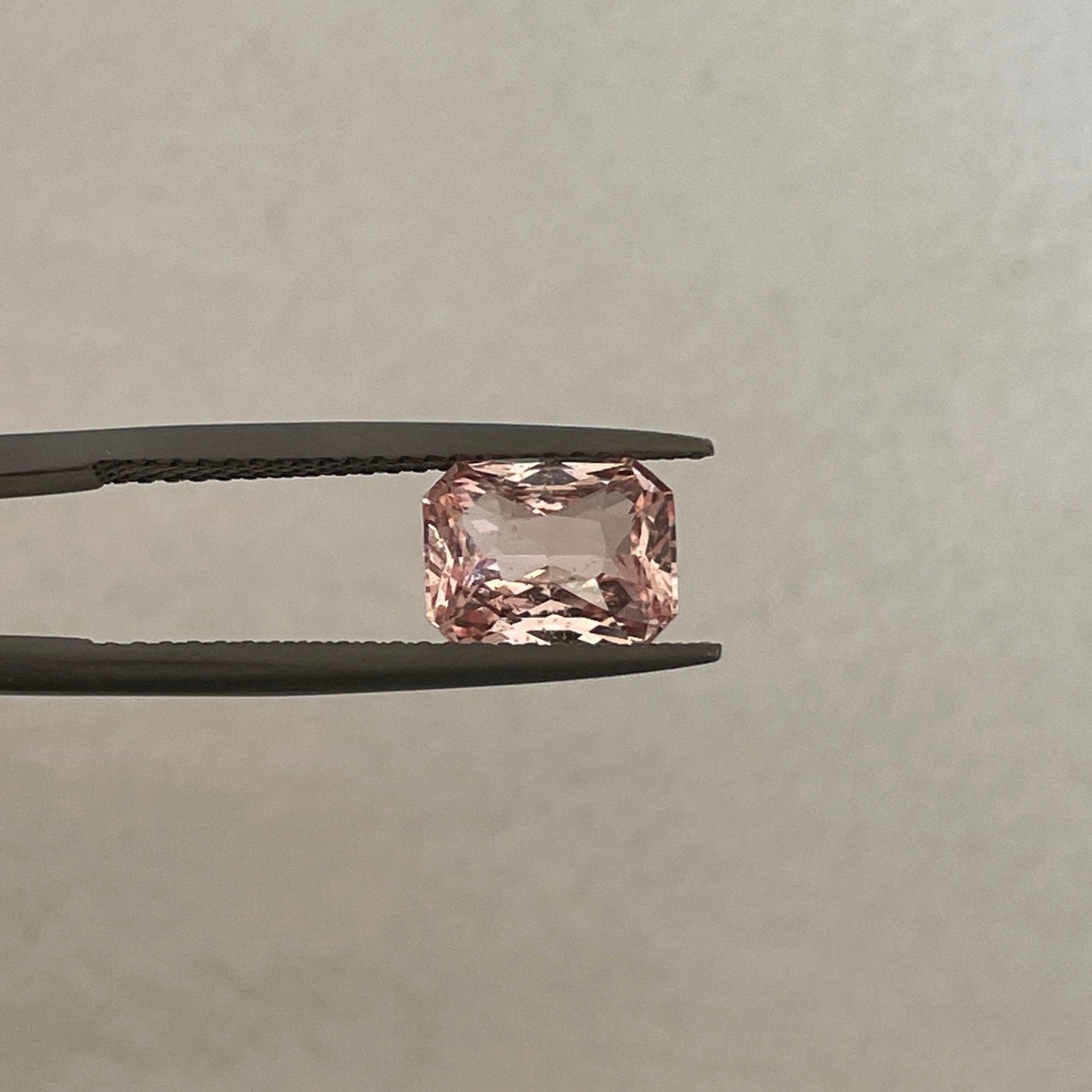 Saphir rose Padparadscha naturel de 2,04 CT de NASHGEMS, mettant en valeur sa couleur vibrante et sa surface de pierre précieuse lisse.