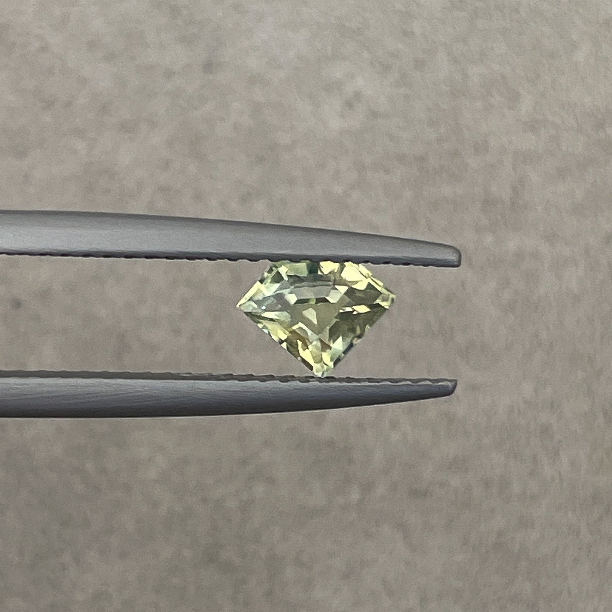 Natural pale green-yellow teal sapphire, 0.72 Ct shield cut loose gemstone by NASHGEMS, ideal for engagement rings or custom jewelry.