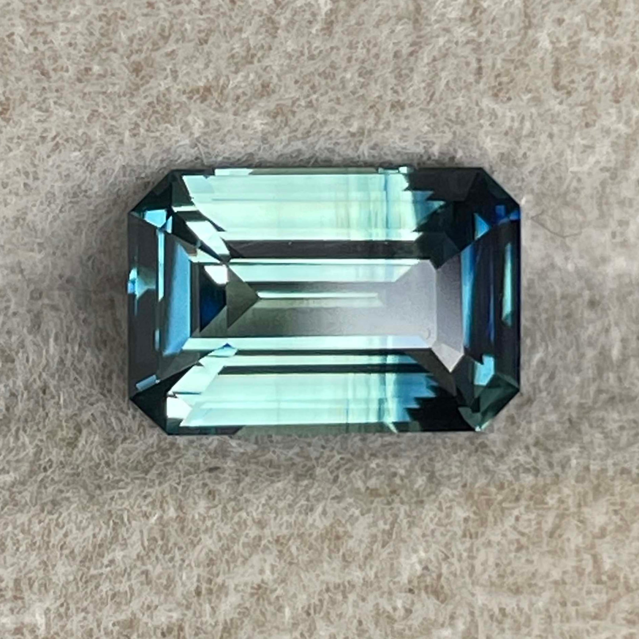Saphir naturel bicolore bleu sarcelle de 2,07 carats taillé en émeraude, présentant des nuances vibrantes bleu-vert pour des bijoux de fiançailles.