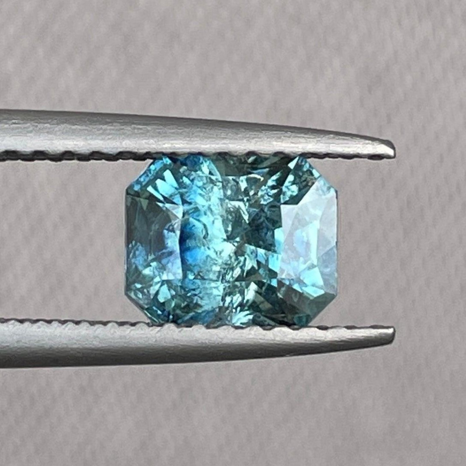 Pierre précieuse saphir sarcelle de NASHGEMS, taille radiant, 5,40 x 6,50 mm, 1,38 carats, présentant une couleur bleu-vert vibrante et une grande clarté.