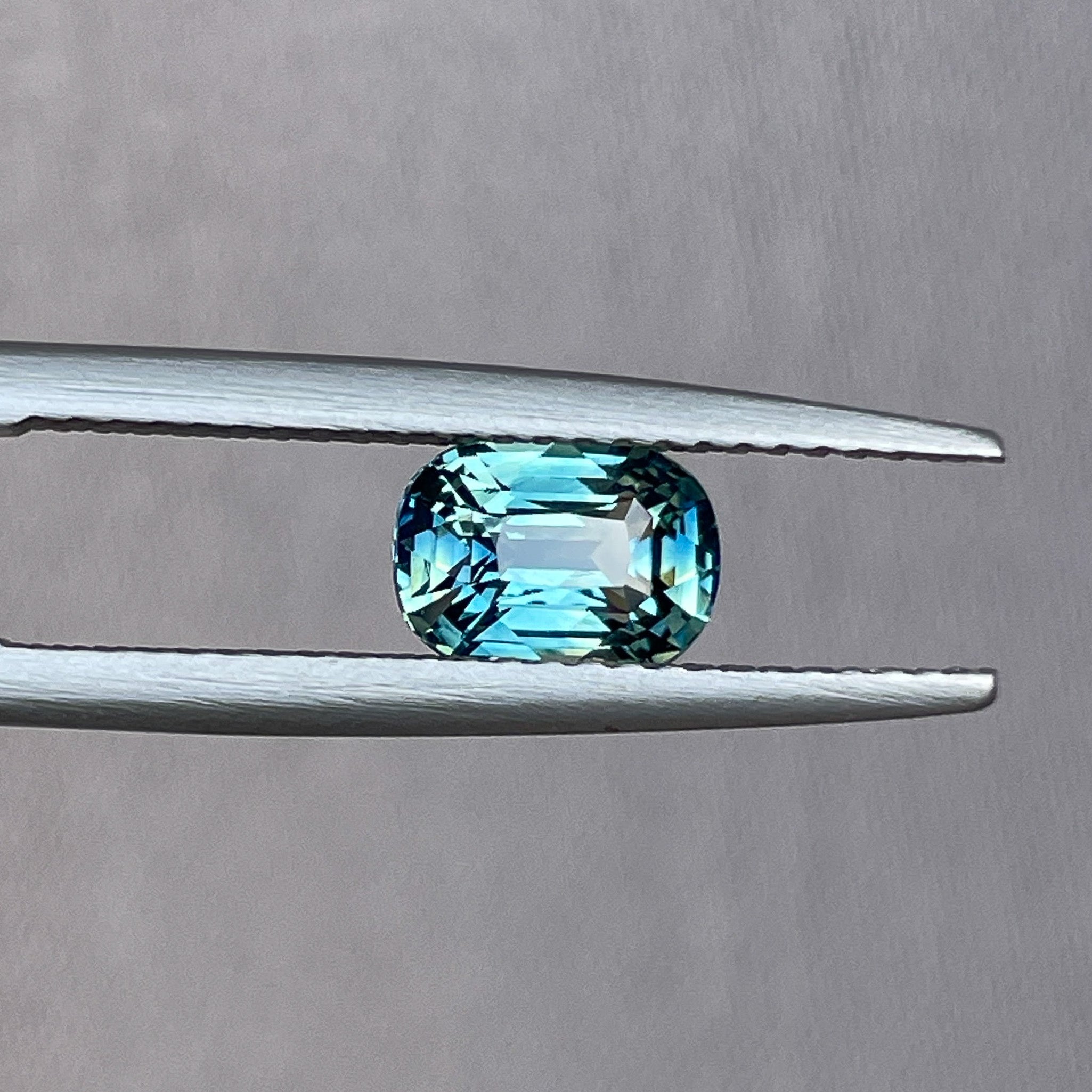Natural teal sapphire 1.36 Ct cushion cut by NASHGEMS, showcasing vibrant blue-green hues, perfect for engagement or custom jewelry.