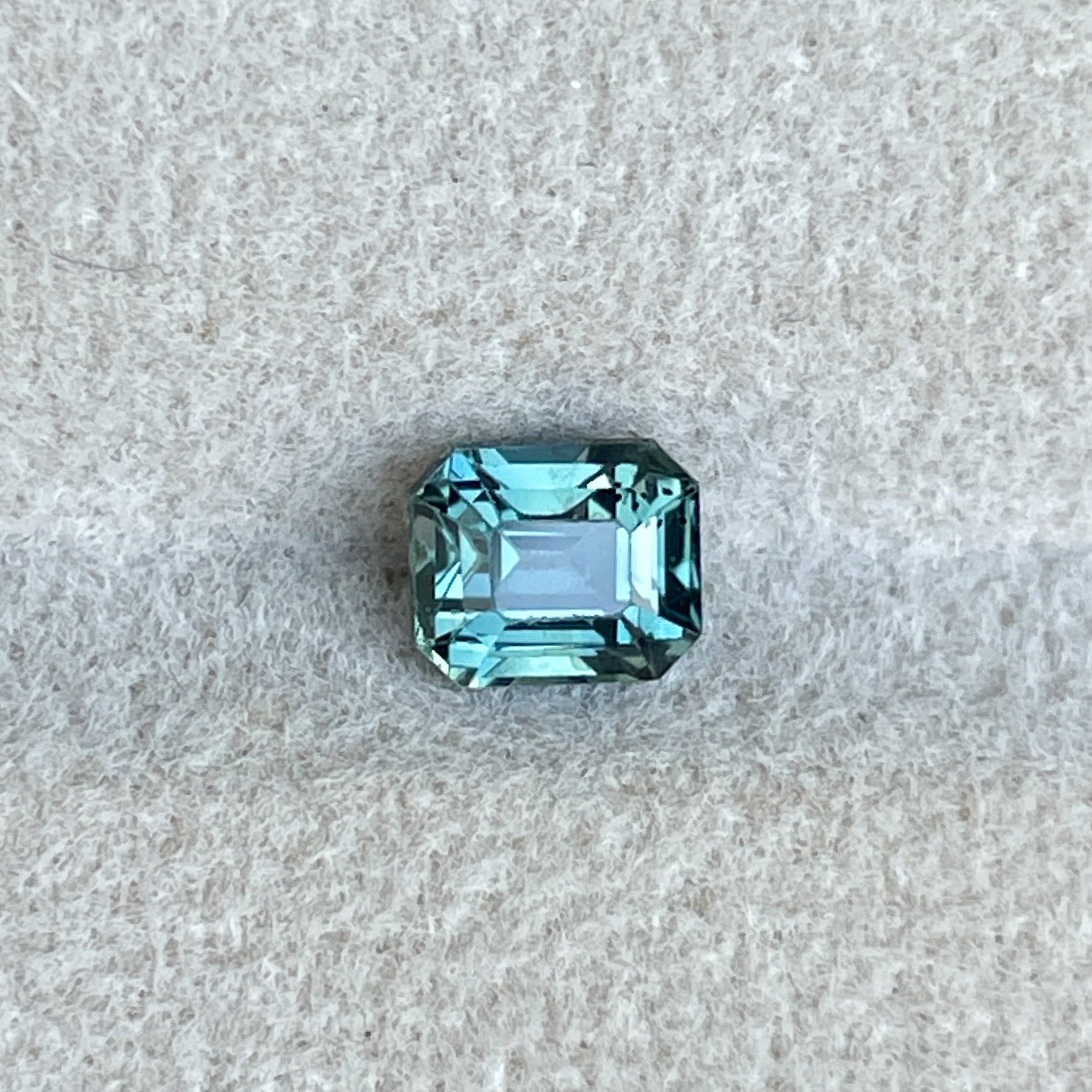Natural teal sapphire from NASHGEMS, 1.05 Ct emerald cut loose gemstone with blue-green hues for jewelry making or engagement rings.