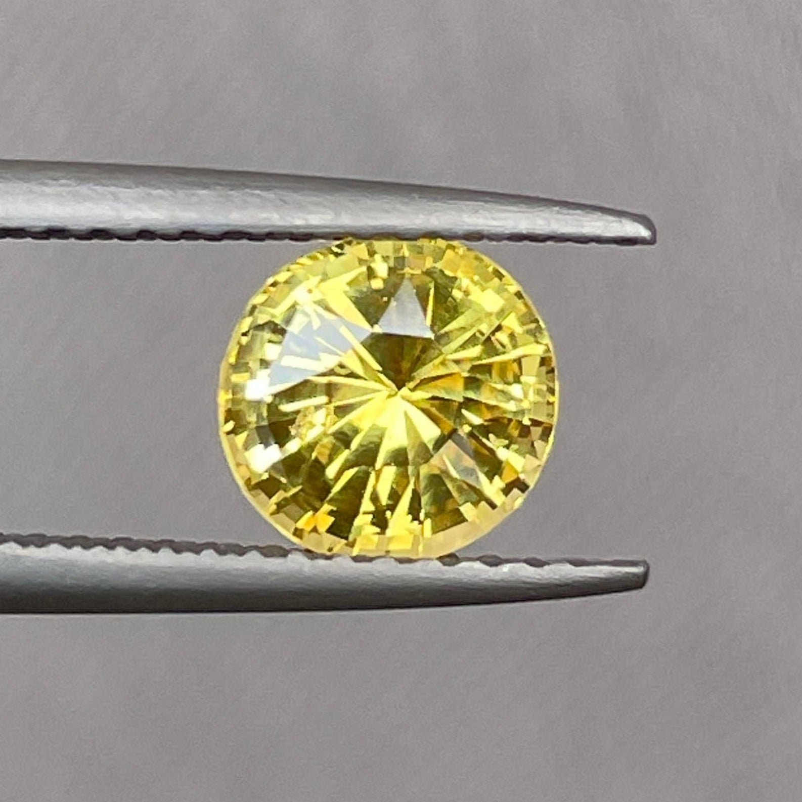 Saphir jaune naturel taille ronde 1,58 carat, pierre précieuse traitée thermiquement, idéale pour bagues ou pendentifs, présentant une couleur jaune éclatante et une grande clarté.