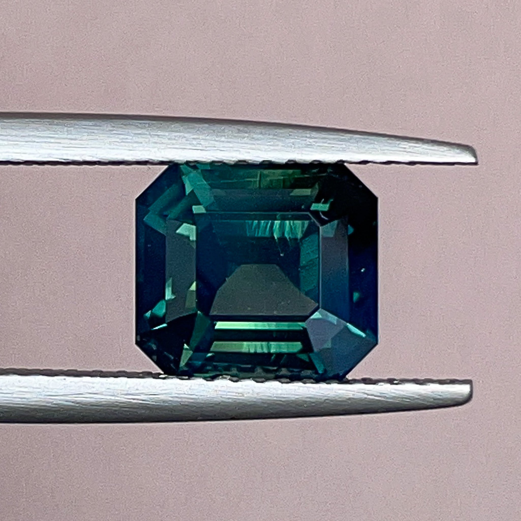 Natural forest green sapphire 3.59 Ct emerald cut loose gemstone by NASHGEMS, showcasing deep teal color and faceted surface.