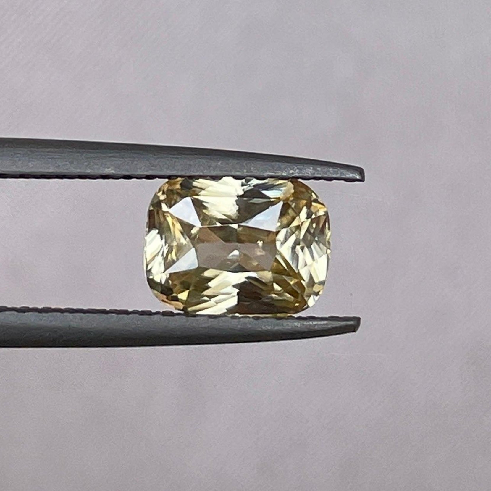 Saphir jaune naturel 1,60 ct avec une teinte pêche jaunâtre de NASHGEMS, mettant en valeur sa couleur vibrante et sa taille lisse.