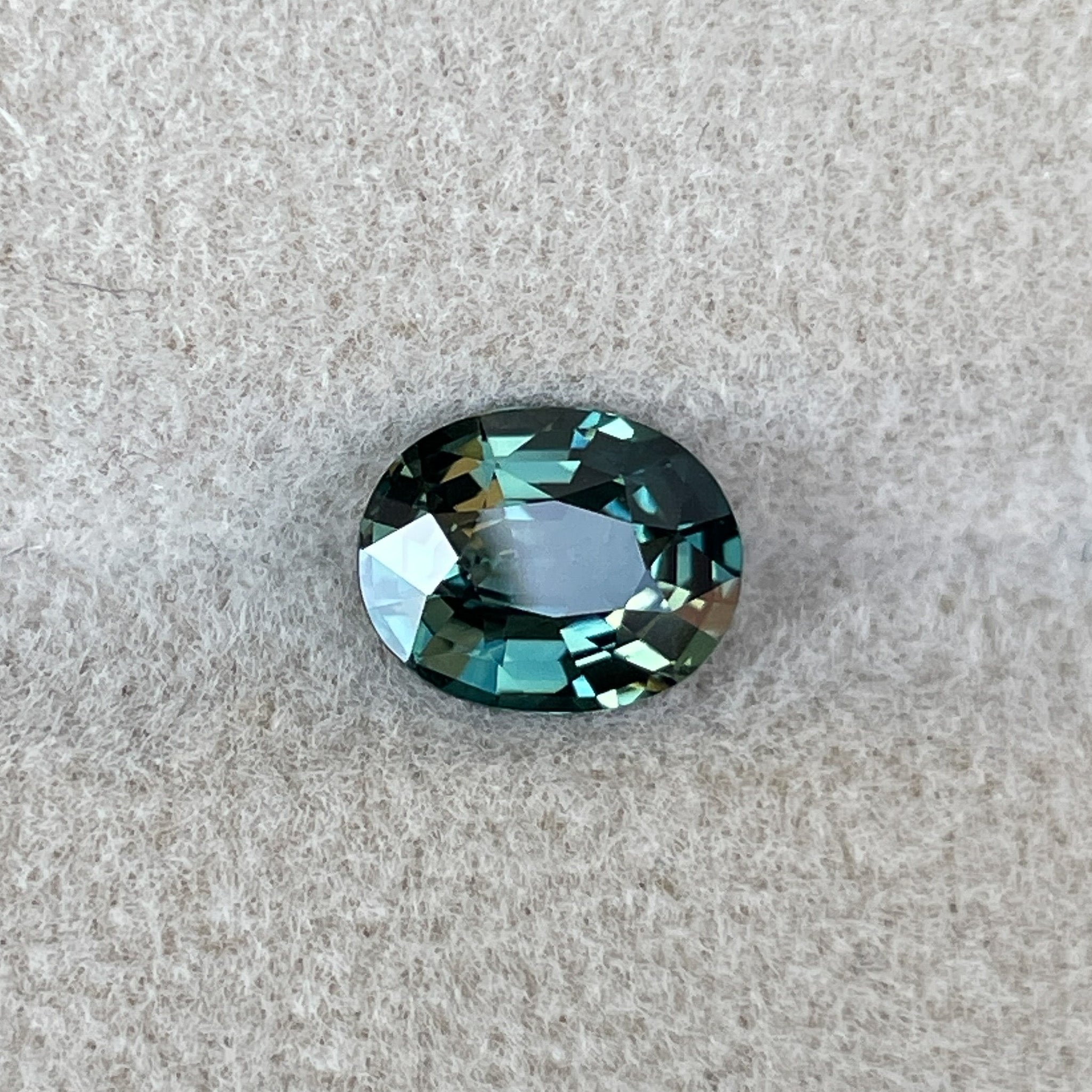 Teal green sapphire loose stone, 1.52 carats, oval cut, heat treated, from NASHGEMS, ideal for engagement rings or custom jewelry.