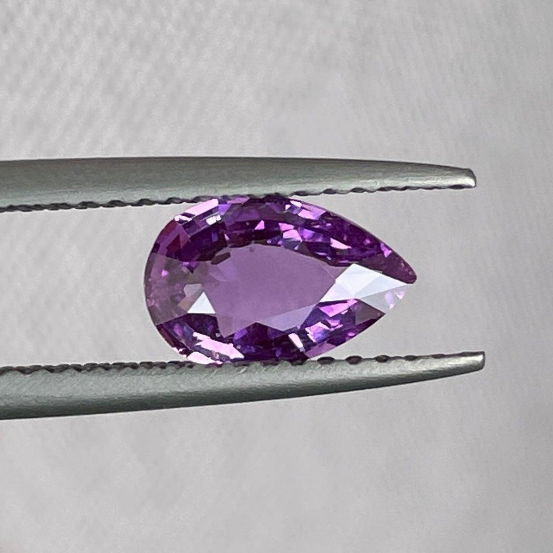 Pierre précieuse saphir rose violet lâche, 1,08 carats, saphir rose naturel pour bijoux, présenté sur un présentoir à bijoux.