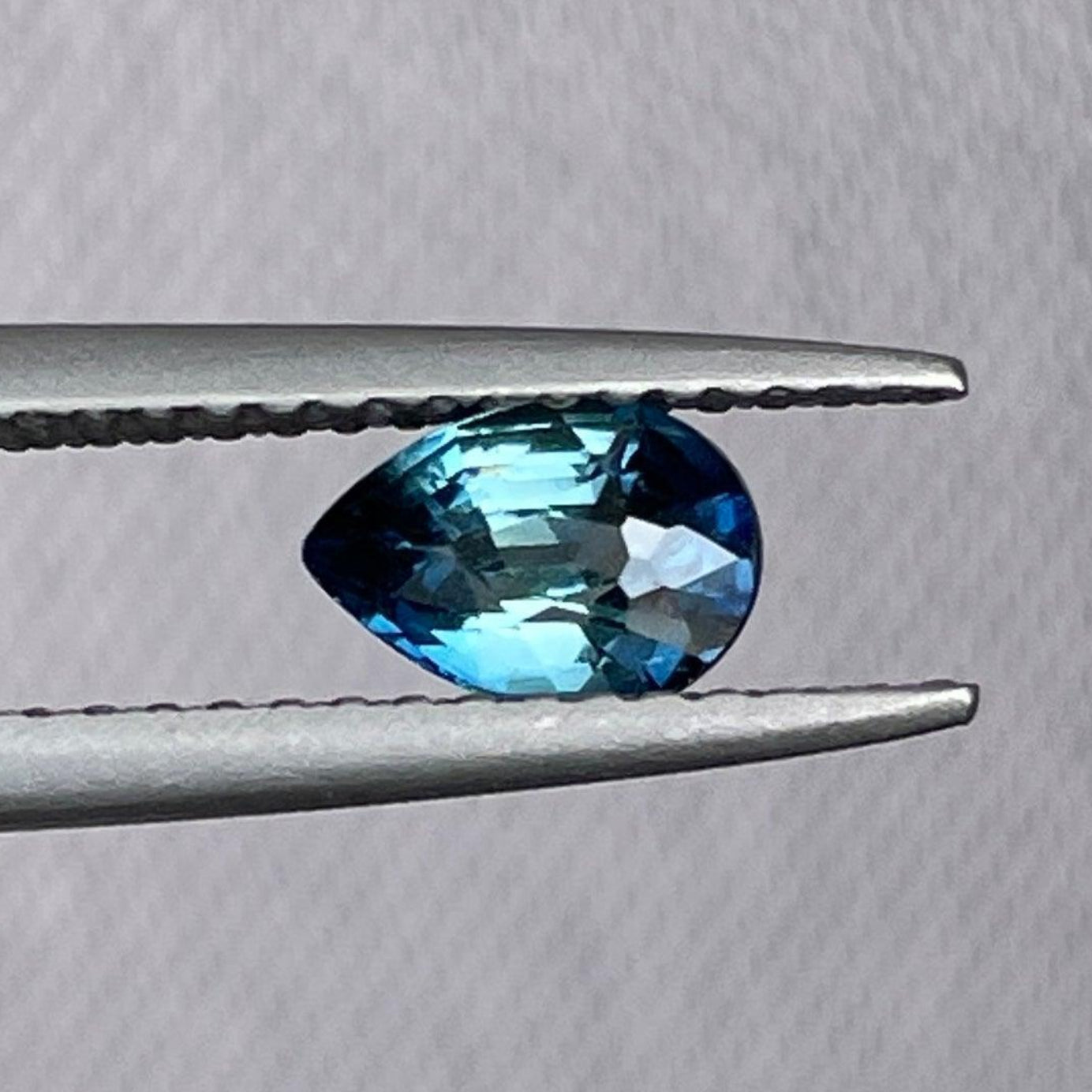 Pierre précieuse saphir bleu sarcelle taille poire de NASHGEMS, 0,71 carats, mesurant 6,30 x 4,40 x 3,30 mm, montrant sa couleur vibrante et sa clarté.