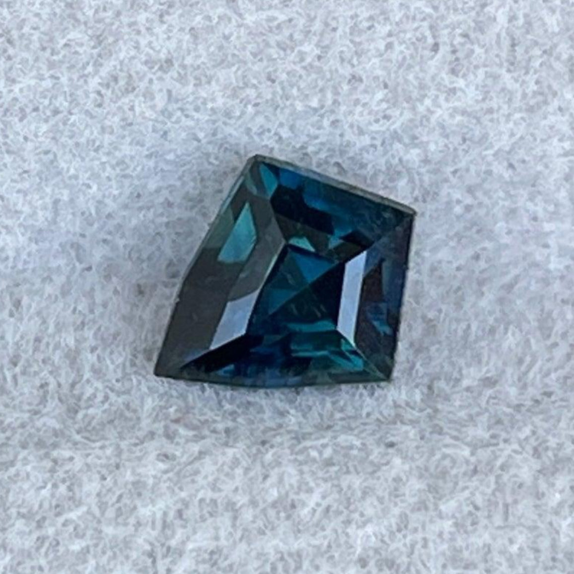 Pierre précieuse saphir sarcelle pesant 0,82 carats, couleur bleu-vert vibrante, de NASHGEMS, vue rapprochée de la gemme polie.