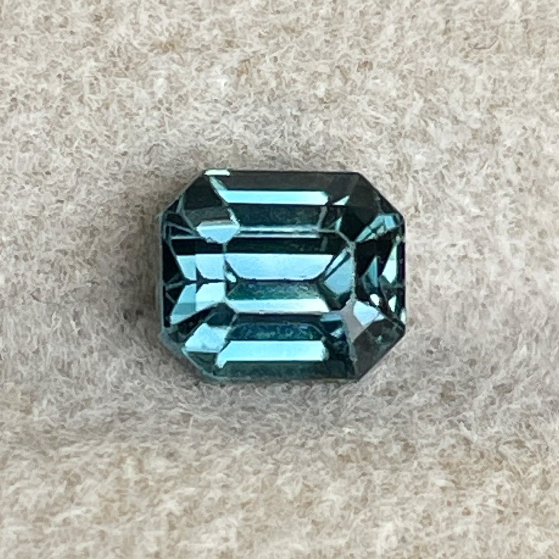 NASHGEMSのナチュラルティールブルーサファイア1.00カラット、エメラルドカットのルースストーン。婚約指輪やカスタムジュエリーに最適です。