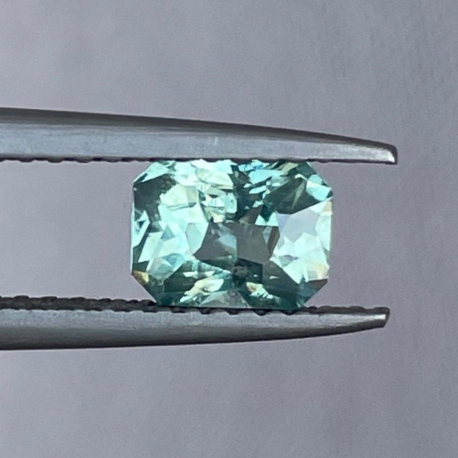 Saphir parti NASHGEMS teal de 0,97 carat pour la fabrication de bijoux, présentant un saphir lâche bicolore aux teintes vibrantes de teal et de bleu.