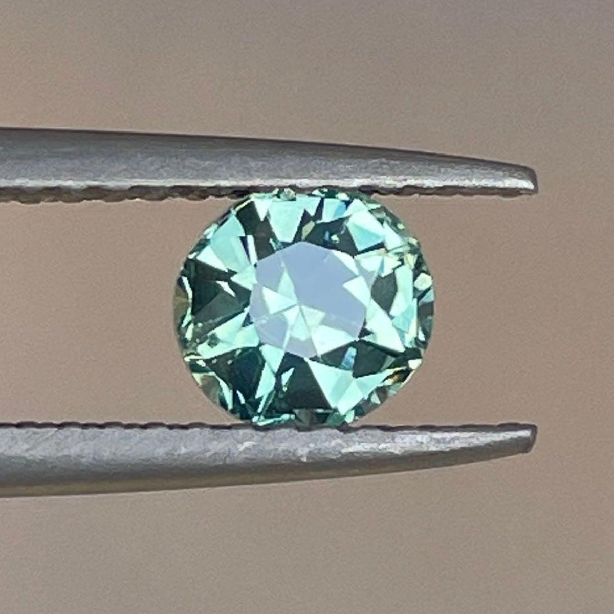 Saphir vert sarcelle 0,89 carat de NASHGEMS présentant une pierre précieuse facettée vibrante avec une teinte verte riche.