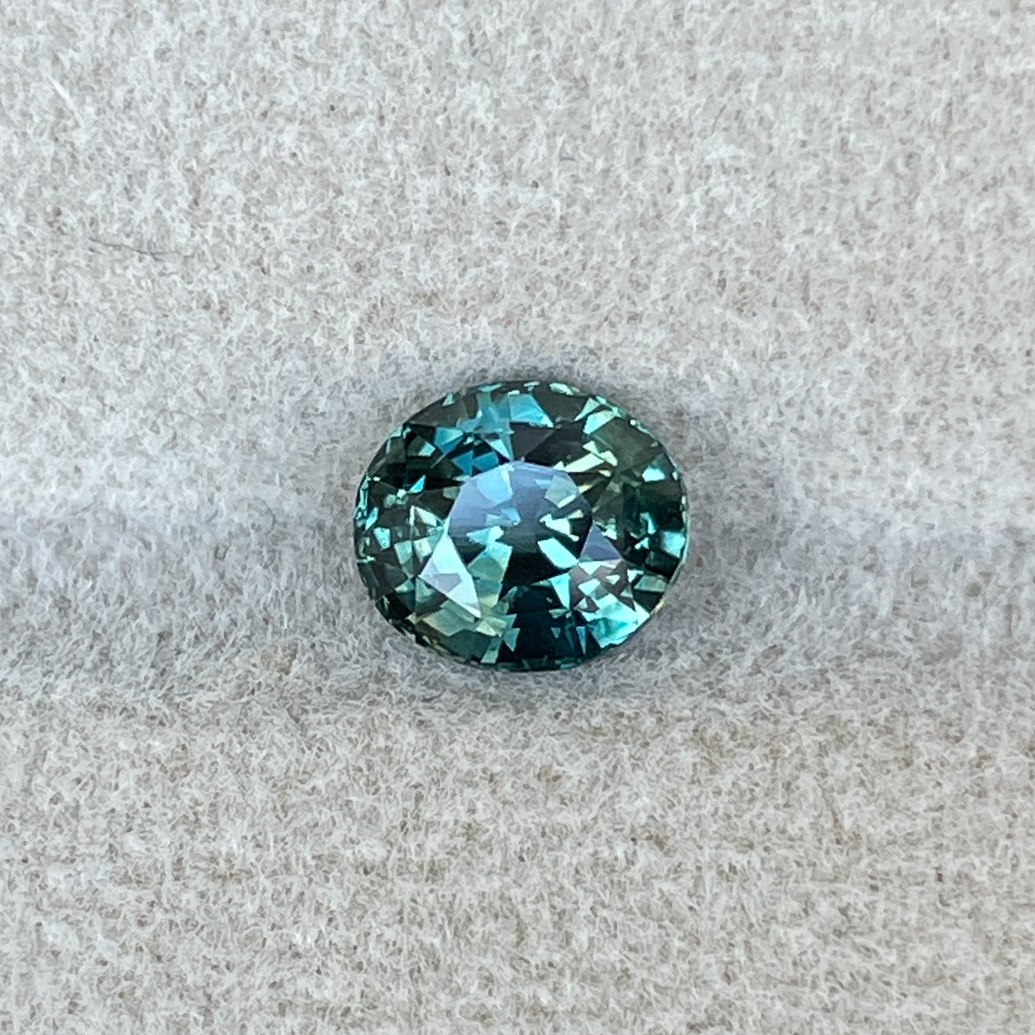 Teal blue-green 1.56 Ct oval cut sapphire loose gemstone by NASHGEMS, ideal for engagement rings or custom jewelry designs.