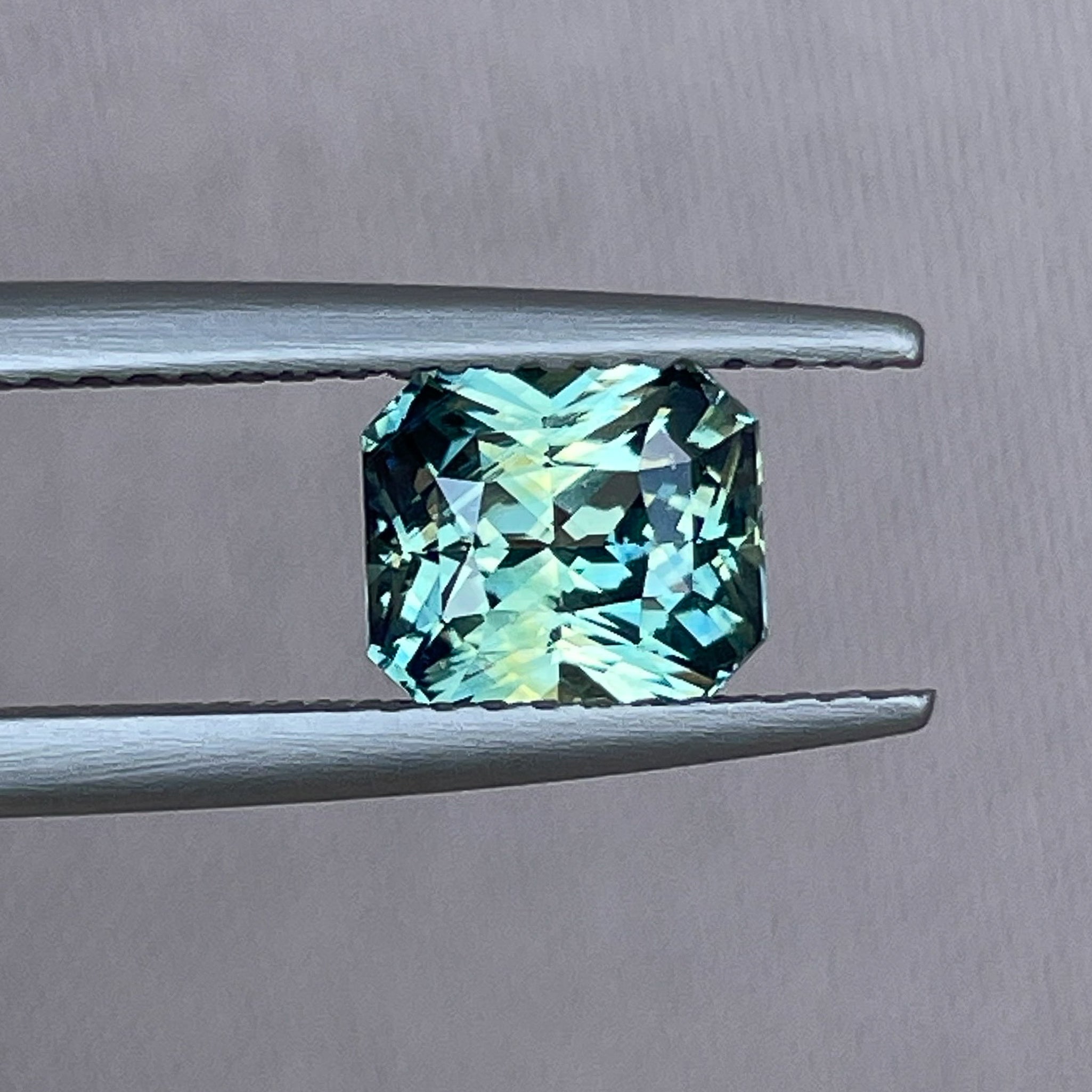 Natural NASHGEMS teal sapphire loose gemstone, 1.65 Ct radiant cut in teal blue-green, perfect for engagement rings.